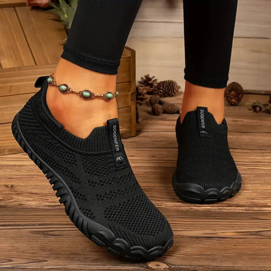 Zapatillas deportivas mujer Barefoot con suela plana y cordones, usadas con jeans mientras se está sentada en un banco en el parque.
