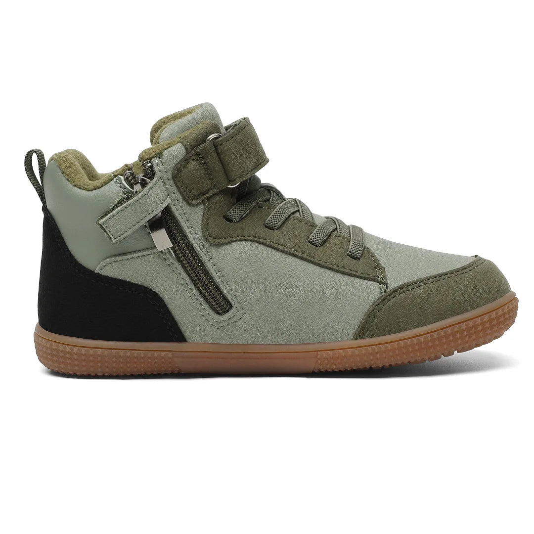 Bebe zapatillas verdes con cremallera lateral y velcro para fomentar la autonomía infantil.